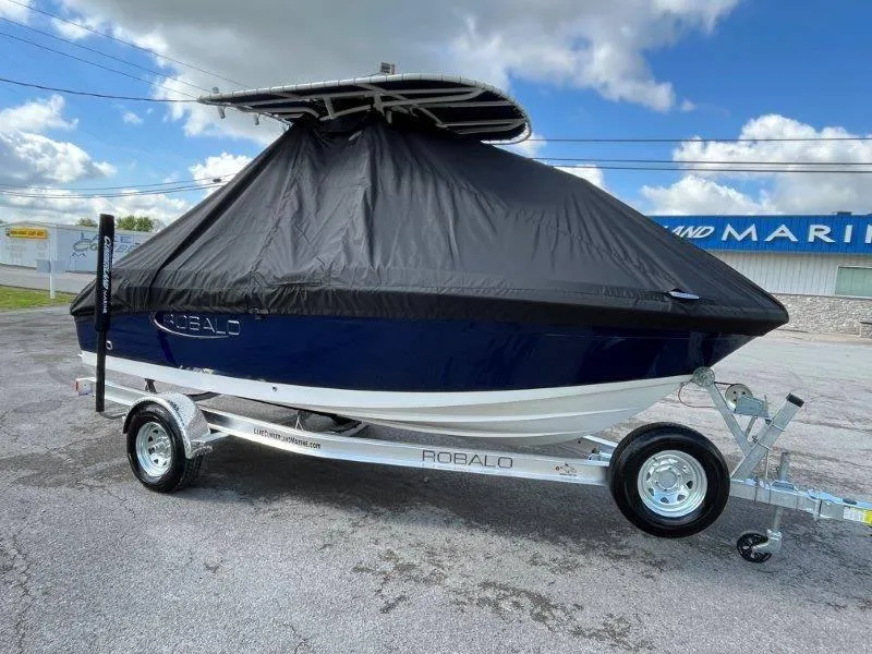 Slide: The Image of 2024 Robalo R180 boat covered on trailer, parked outdoors. - 12