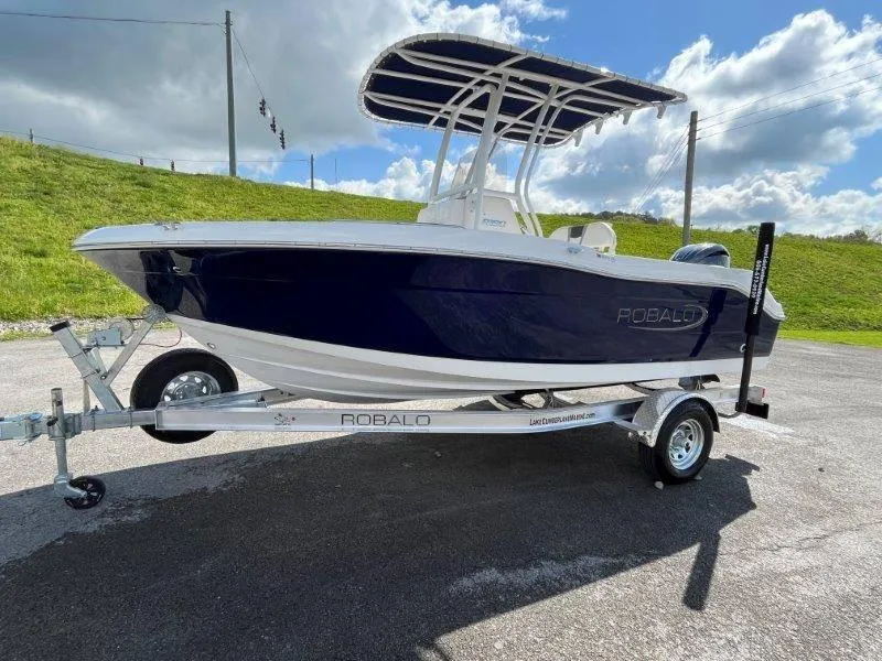 Slide: The Image of 2024 Robalo R180 boat on trailer under blue sky. - 17