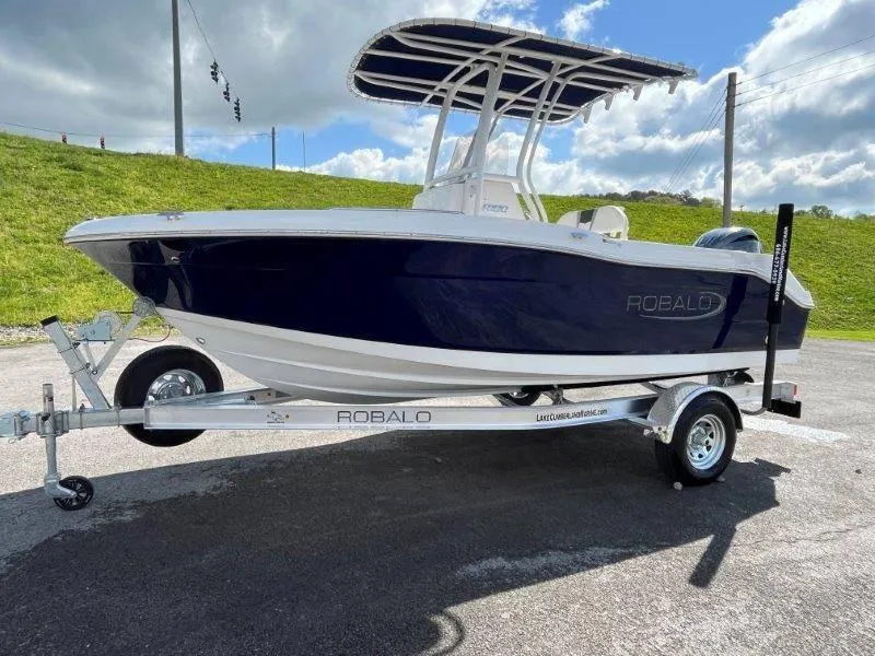 Slide: The Image of 2024 Robalo R180 boat on trailer, parked outdoors under a cloudy sky. - 21