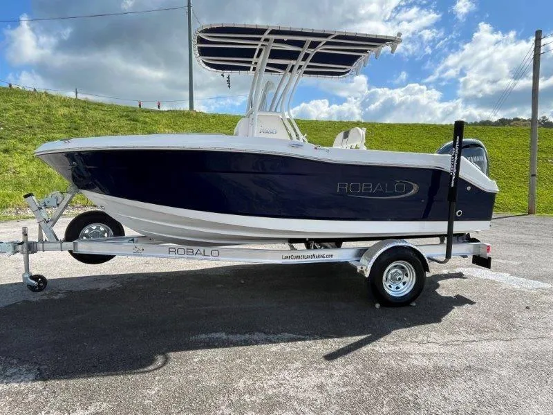 Slide: The Image of 2024 Robalo R180 boat on trailer under blue sky. - 28