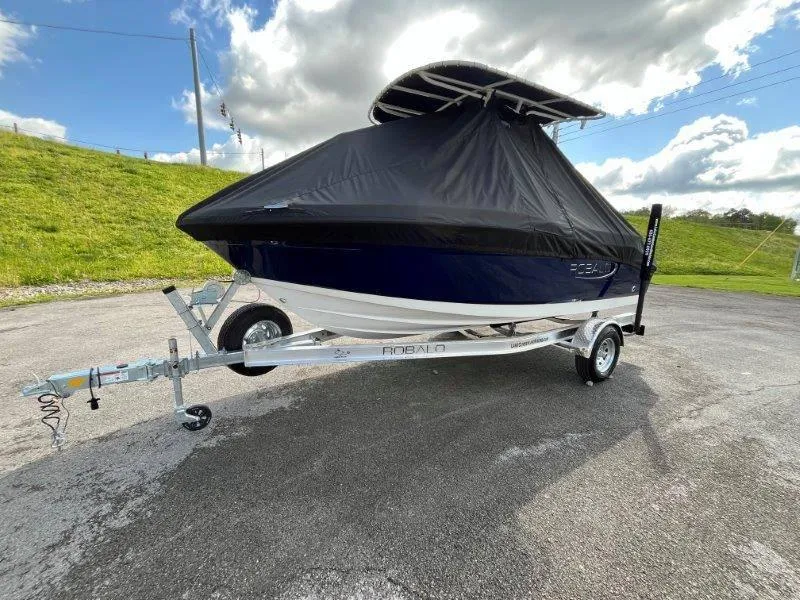 Slide: The Image of 2024 Robalo R180 boat on trailer with cover, parked outdoors. - 7