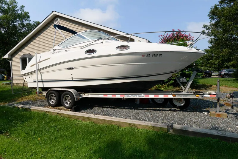The Image of 2008 Sea Ray 240 Sundancer boat on trailer, parked beside a house. - 0