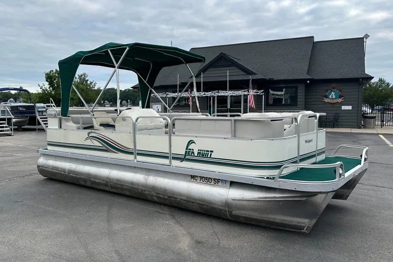 Slide: The Image of 2001 Sea Hunt 20 pontoon boat with green canopy, parked on pavement. - 0