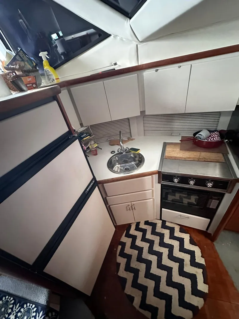 Slide: The Image of 1993 Carver 33 Aft Cabin kitchen with stove, sink, and chevron rug. - 15