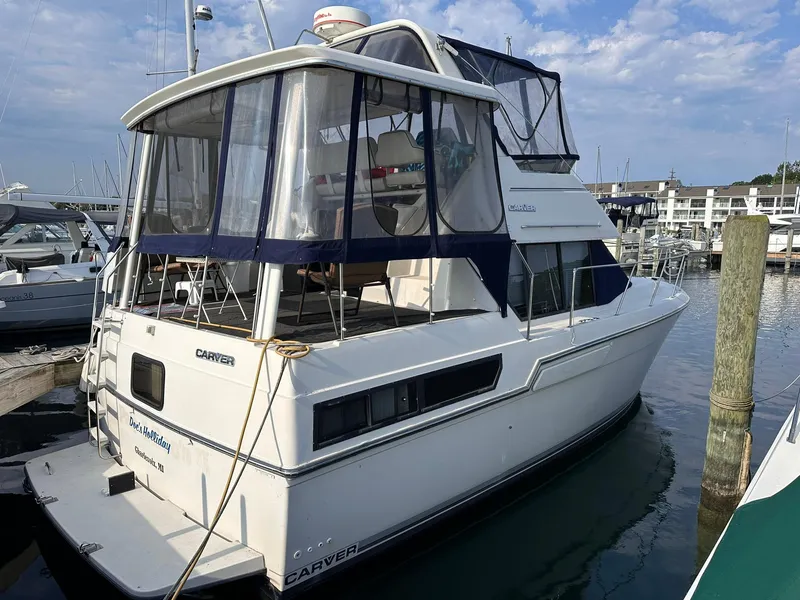 Slide: The Image of 1993 Carver 33 Aft Cabin yacht docked at marina, featuring blue canopy and white hull. - 2