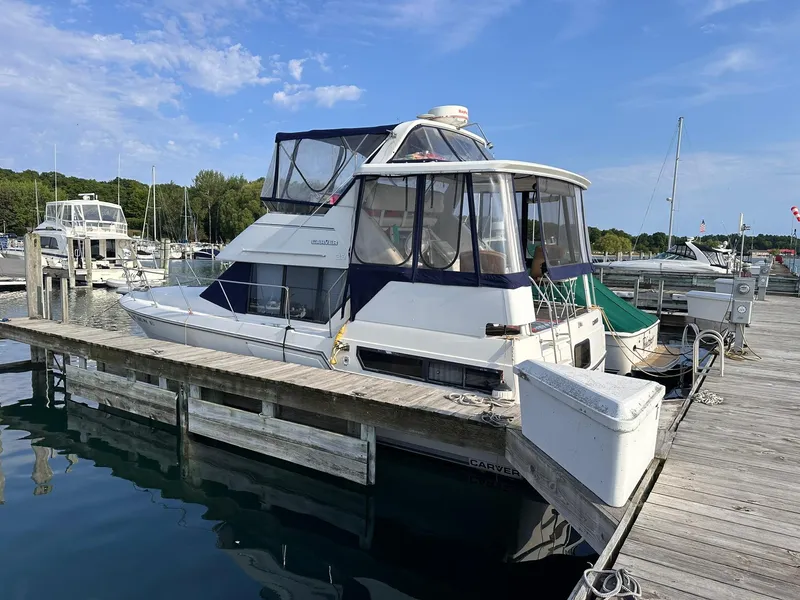 The Image of 1993 Carver 33 Aft Cabin yacht docked at a marina under a clear blue sky. - 0