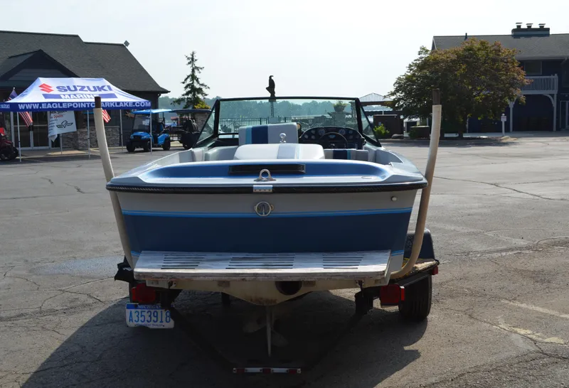 Slide: The Image of 1989 Correct Craft Ski Nautique boat on trailer, parked in a lot with tents and buildings. - 3