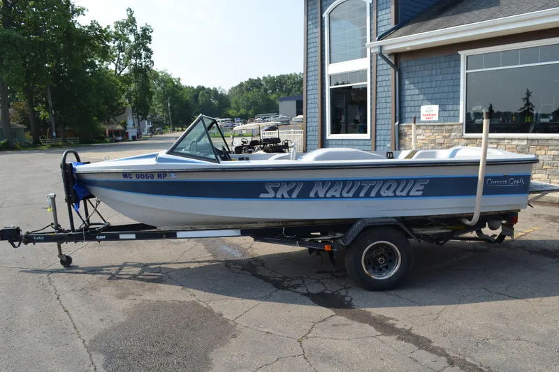 Slide: The Image of 1989 Correct Craft Ski Nautique boat on trailer, parked outside a building. - 4