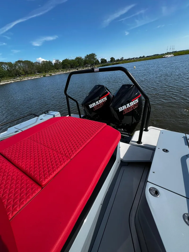 Slide: The Image of 2022 BRABUS Shadow 500 Cabin boat with red seating and dual engines on a calm lake. - 11