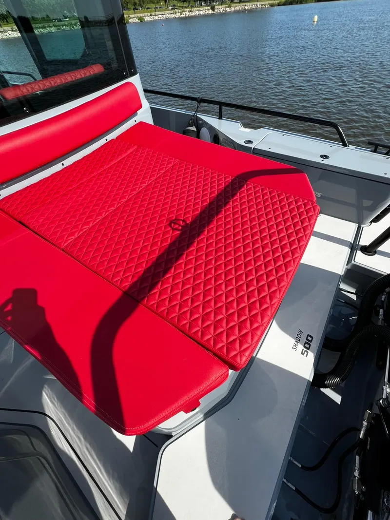 Slide: The Image of 2022 BRABUS Shadow 500 Cabin with red quilted seating, docked by the water. - 13