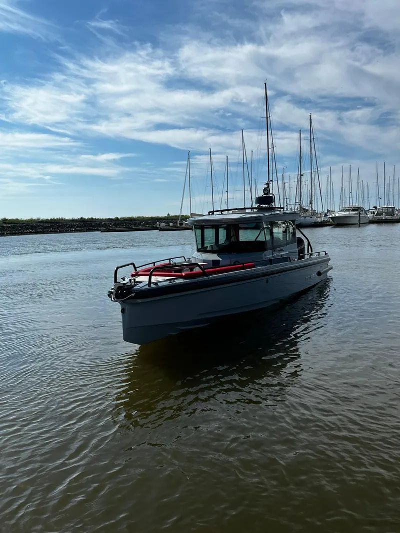 Slide: The Image of 2022 BRABUS Shadow 500 Cabin boat on calm water with sailboats in the background. - 6