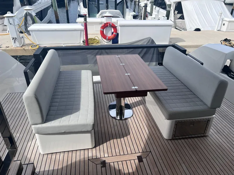 Slide: The Image of 2024 Astondoa AS5 yacht deck with cushioned seating and wooden table. - 11