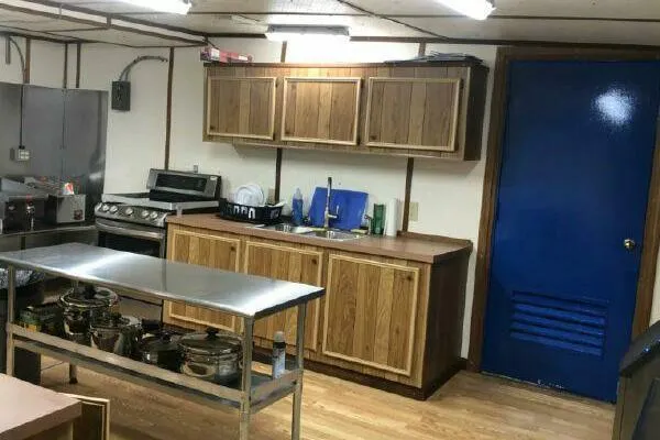 Slide: The Image of Industrial kitchen with wooden cabinets, stainless steel appliances, and a blue door. AlumaCat 100, 2000. - 12