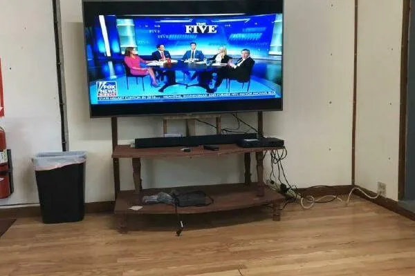 Slide: The Image of TV showing news panel discussion in a living room with wooden flooring. - 14