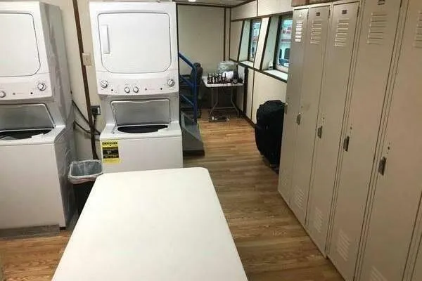 Slide: The Image of Laundry room with stacked washers, dryers, lockers, and folding table on wooden floor. - 16
