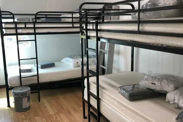 Slide: The Image of Room with metal bunk beds, mattresses, and bedding on wooden floor. - 18