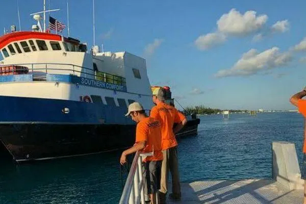 Slide: The Image of AlumaCat 100 ferry docked, crew in orange shirts, clear sky, 2000 model. - 19