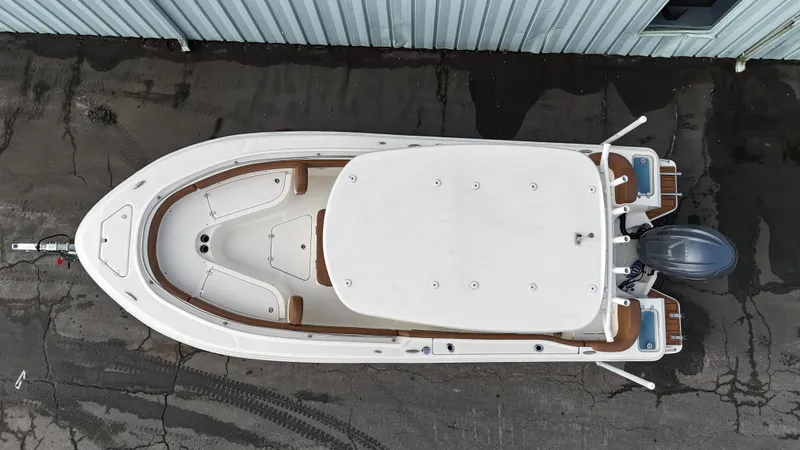 Slide: The Image of Top view of 2024 Pioneer 222 Islander boat, parked on pavement near a building. - 2