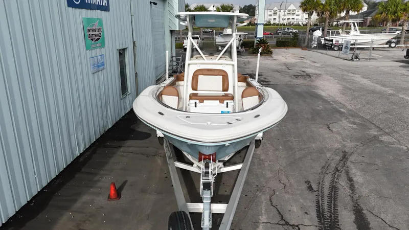 Slide: The Image of 2024 Pioneer 222 Islander boat on trailer, parked outside a marina. - 10