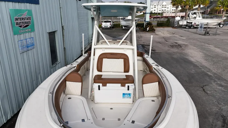 Slide: The Image of 2024 Pioneer 222 Islander boat with white and brown seating, docked near a building. - 9
