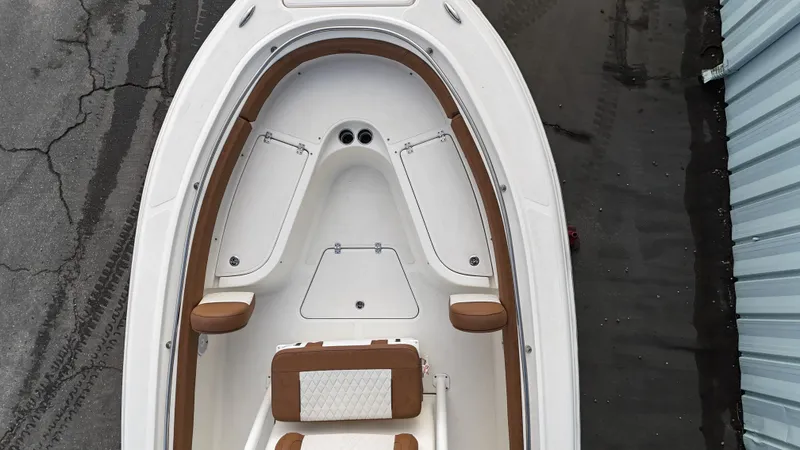 Slide: The Image of 2024 Pioneer 222 Islander boat, top view, white and brown interior, docked on wet pavement. - 6