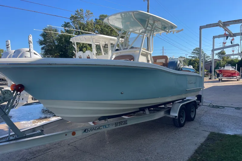 Slide: The Image of 2024 Pioneer 222 Islander boat on trailer, dockside, under clear blue sky. - 2