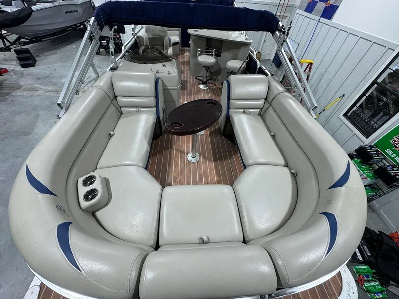 Slide: The Image of 2014 Berkshire 250E STS pontoon boat with spacious seating and table, indoor showroom display. - 8