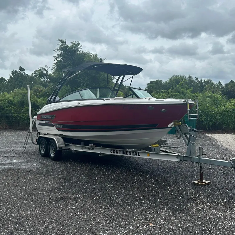 Slide: The Image of 2021 Monterey 215 Super Sport boat on trailer, parked outdoors under cloudy sky. - 17