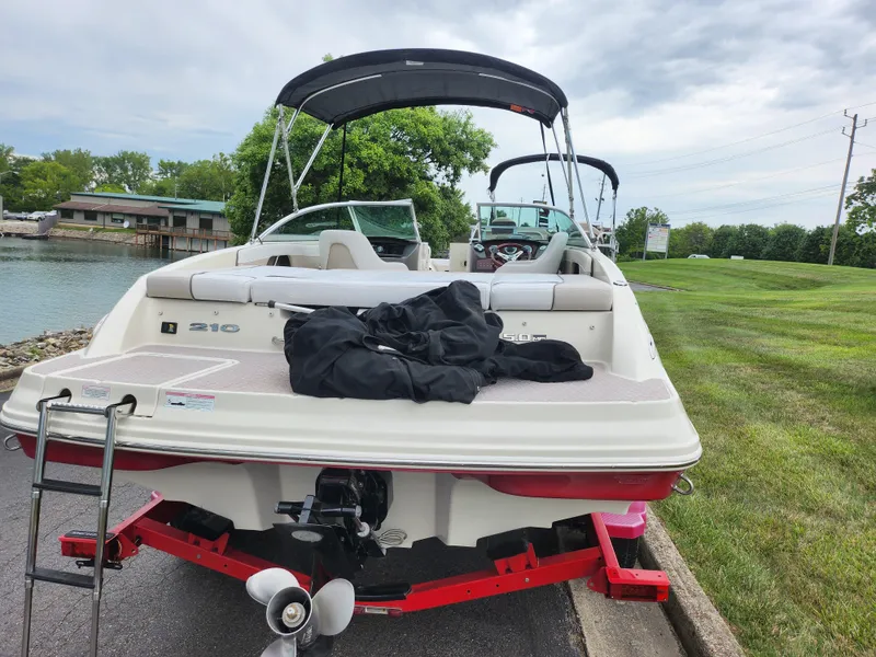 Slide: The Image of 2010 Sea Ray 210 Select boat on trailer by lakeside, overcast sky. - 2