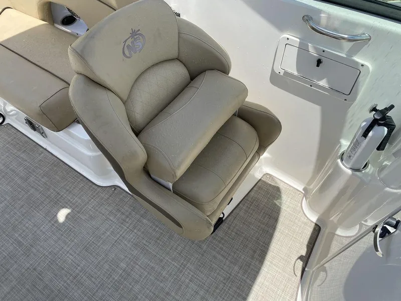 Slide: The Image of 2019 NauticStar 243 DC boat seat with beige upholstery and armrest. - 1