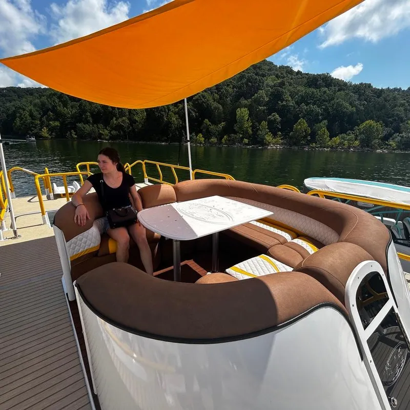 Slide: The Image of Woman relaxing on 2025 Aloha Pontoon 40' Sky View, under orange canopy, by a lake. - 16