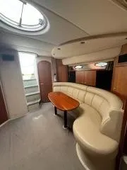 Slide: The Image of 2001 Cruisers Yachts 3870 Express interior with curved seating and wooden table. - 7