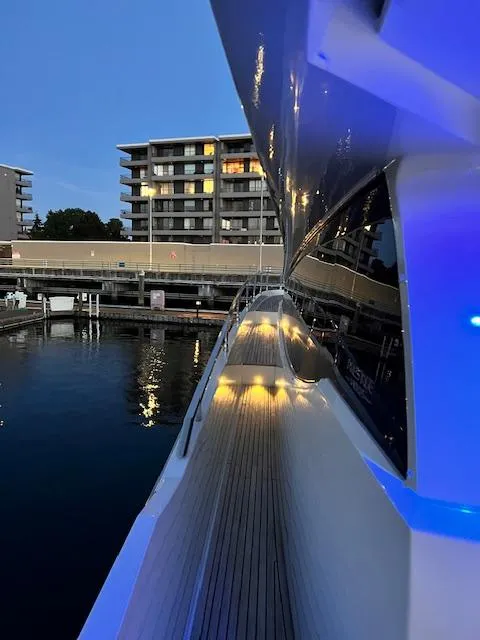 Slide: The Image of Prestige 750 yacht docked at marina, evening lights reflecting on water. - 8
