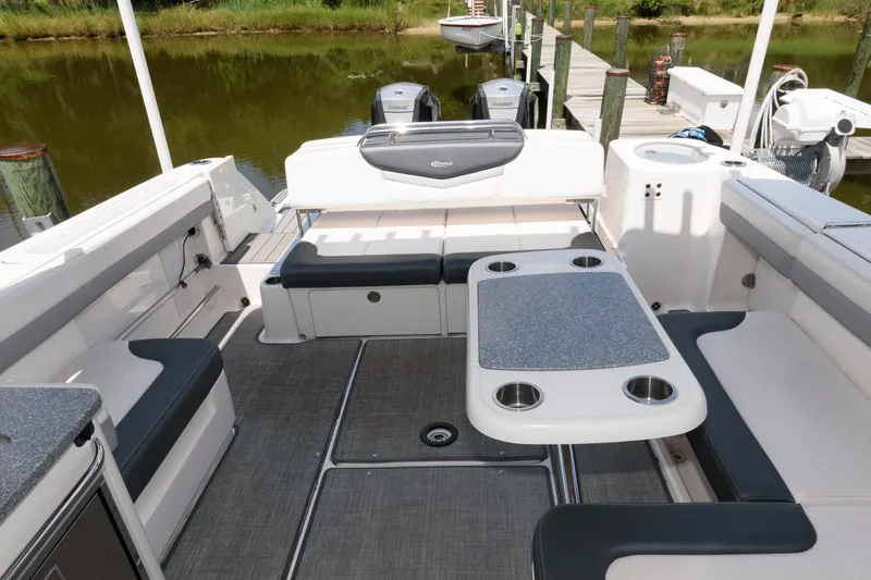Slide: The Image of 2020 Robalo R317 Dual Console boat interior with seating and table, docked by a lake. - 12