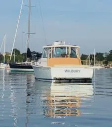 Slide: The Image of 2006 Hunt Yachts Surfhunter 33 on calm water, named "WILBURY," with sailboats in the background. - 3
