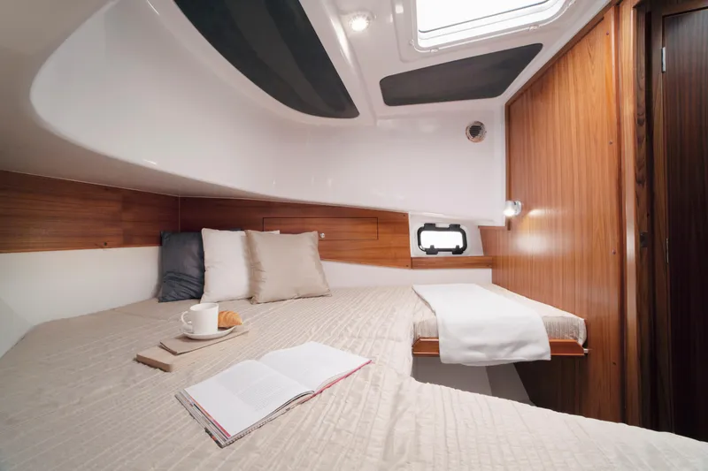 Slide: The Image of 2024 Sargo 31 cabin interior with cozy bed, open book, and cup of coffee. - 8