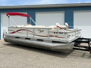 Slide: The Image of 2006 Crest Super Sport pontoon boat with red canopy parked near blue garage doors. - 1