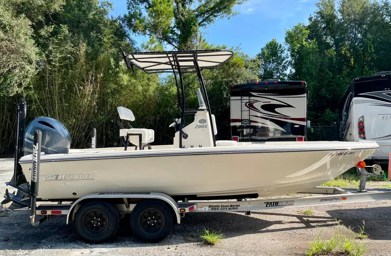 The Image of Pathfinder 2005 TRS boat on trailer, parked outdoors, surrounded by trees and RVs. - 1