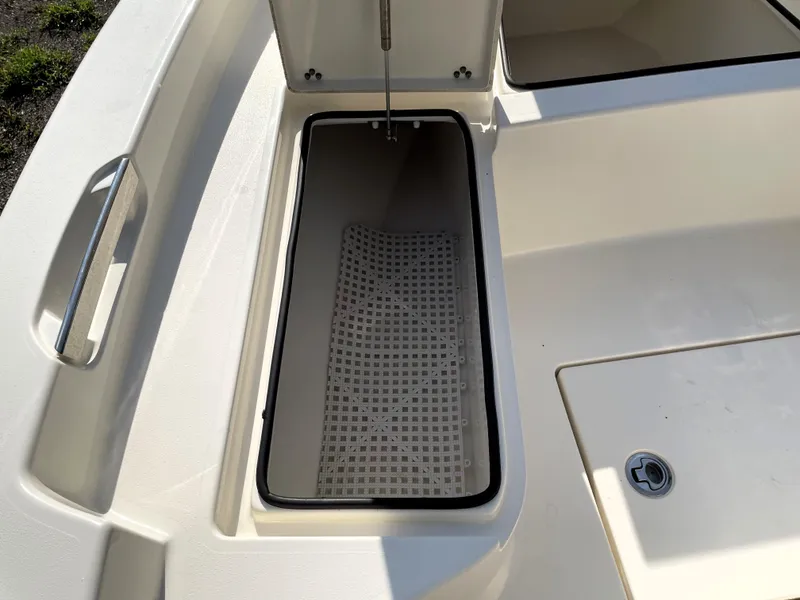 Slide: The Image of Open storage compartment on a 2021 Pathfinder 2005 TRS boat, featuring a drain plug. - 24