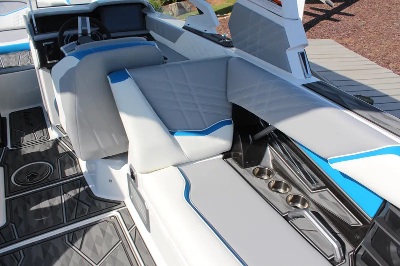 Slide: The Image of 2024 Tigé Ultré 25ZX boat interior with white and blue seating, cup holders, and modern design. - 10