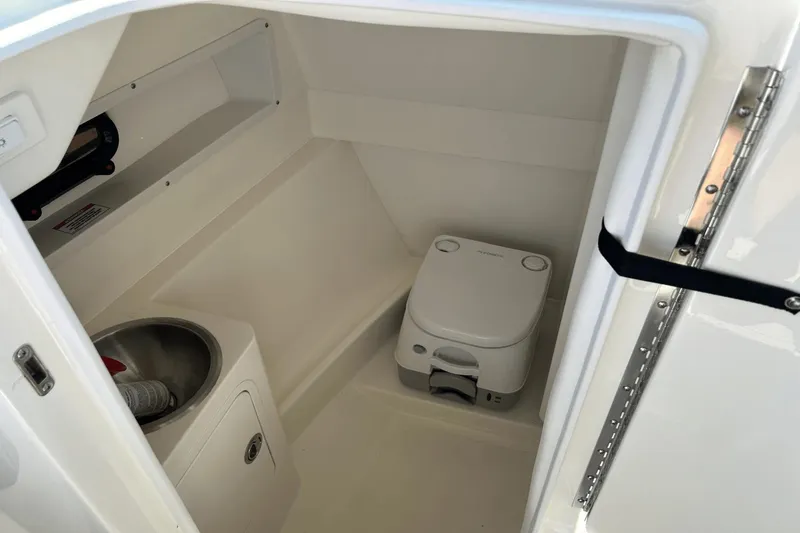 Slide: The Image of 2022 Sea Ray 270 Sundeck Outboard interior with compact marine toilet and sink. - 16