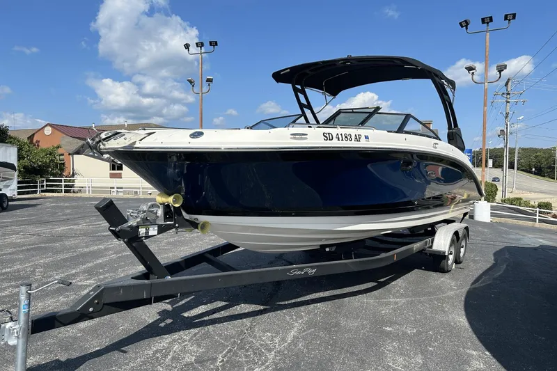 Slide: The Image of 2022 Sea Ray 270 Sundeck Outboard boat on trailer, parked outdoors under blue sky. - 2