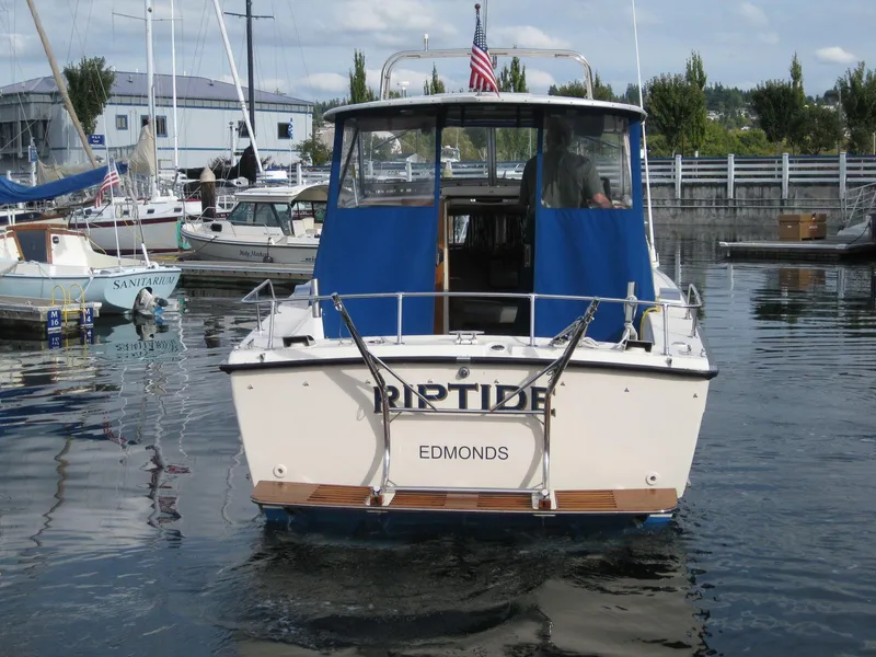Slide: The Image of 1977 Chris-Craft 28' Cruiser docked, rear view with blue canopy and American flag. - 1