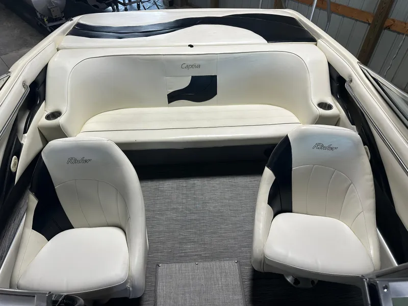 Slide: The Image of 1999 Rinker 212 Bowrider Captiva interior with white and black seating in a boat garage. - 25