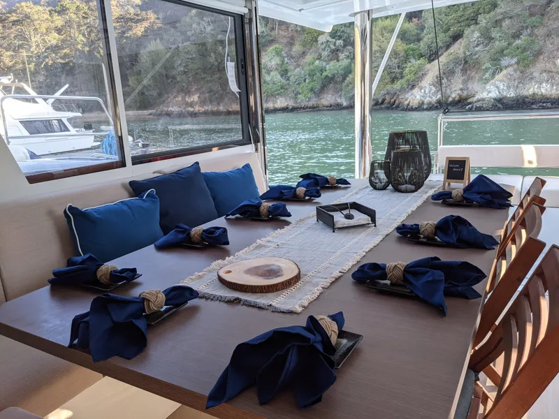 Slide: The Image of Elegant dining setup on a 2021 Bali 4.8 yacht with blue napkins and scenic water view. - 21