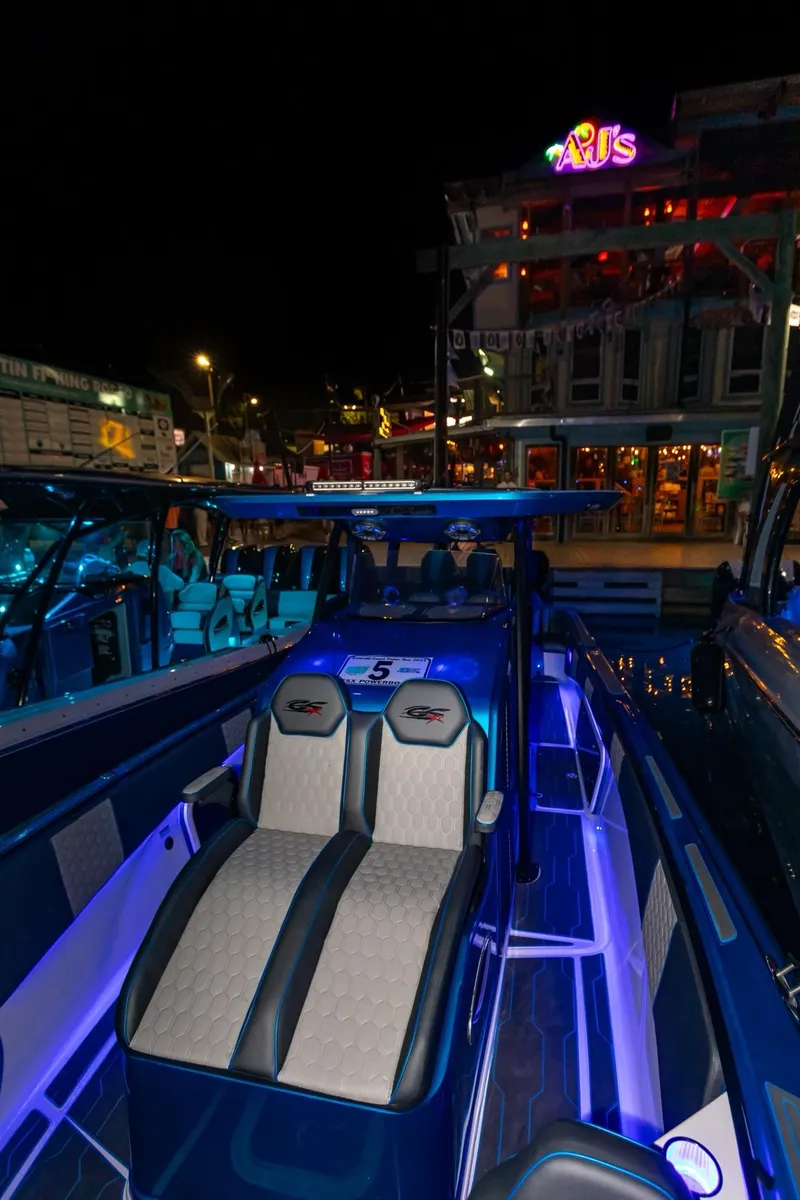 Slide: The Image of 2024 Glasstream GSX 36 boat with illuminated interior at night, docked near a lively waterfront. - 12