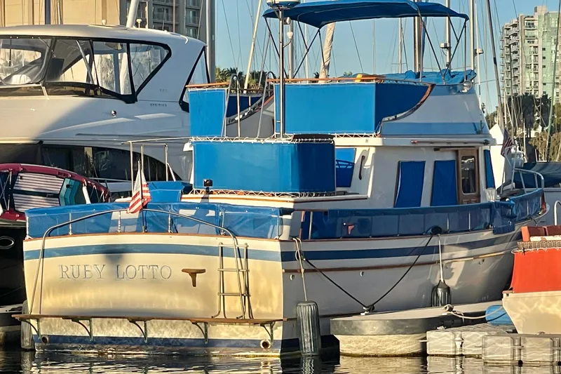 Slide: The Image of 1979 Golden Star Aft Cabin boat docked in marina, featuring blue accents and American flag. - 6