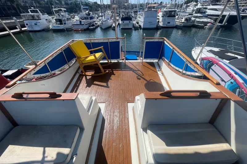Slide: The Image of 1979 Golden Star Aft Cabin boat deck with yellow chair, docked in marina. - 8