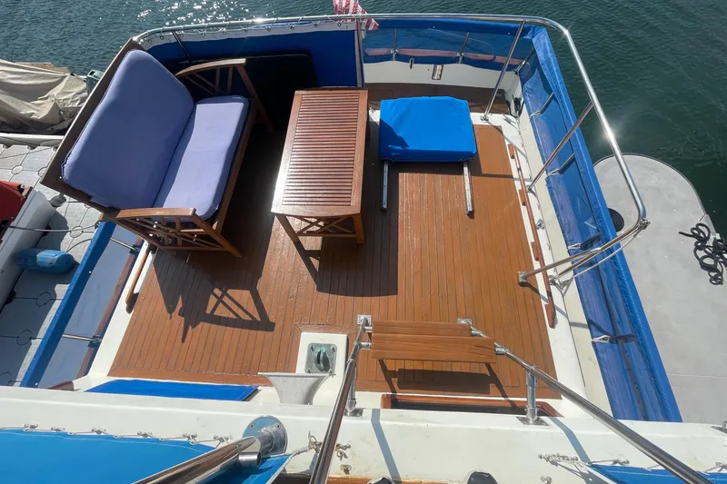 Slide: The Image of 1979 Golden Star Aft Cabin boat deck with seating and table, overlooking water. - 9