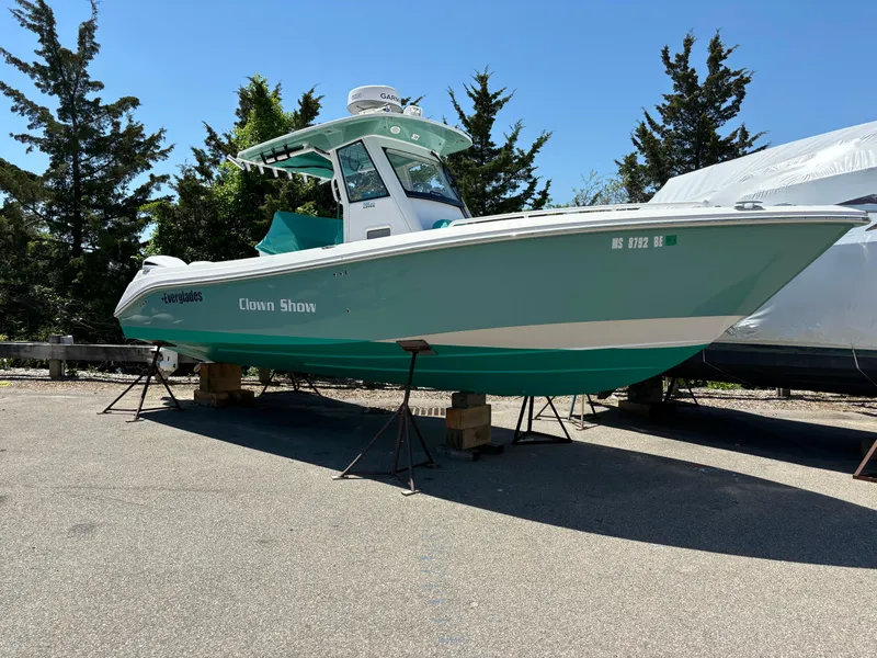 The Image of 2014 Everglades 295 boat on stands, teal color, parked outdoors. - 1